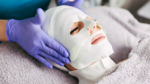 Monika Badauta behandelt Frau mit einer Gesichtsmaske